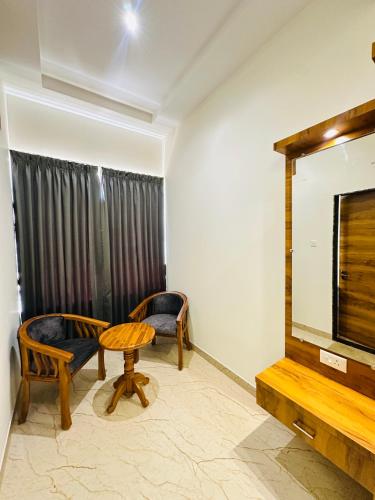 a room with two chairs and a table and a television at Shambhavi Hotel And Convention Centre in Udupi