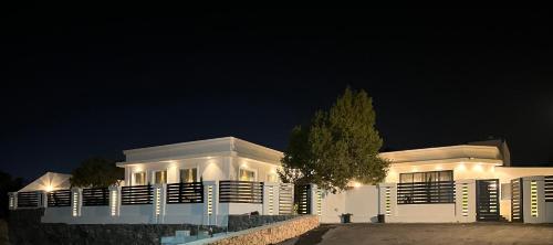 un edificio bianco con un albero di fronte di شاليهات روز a Al Shafa