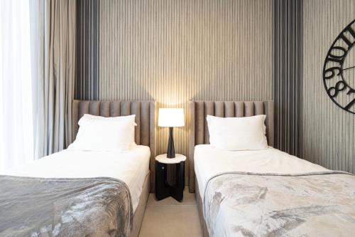 a bedroom with two beds and a lamp between them at 2BR The Al Jada Dream by Blue Cloud Holidays in Sharjah