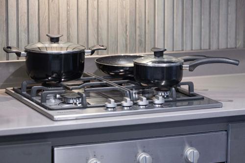 two pots and pans sitting on top of a stove at 2BR The Al Jada Dream by Blue Cloud Holidays in Sharjah