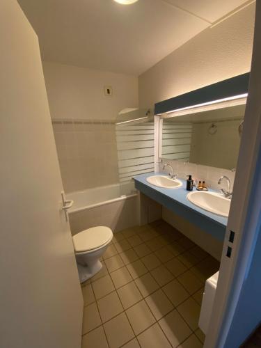une salle de bain avec deux lavabos et un WC et un miroir dans l'établissement auberge des trois ami-es, à Vinezac