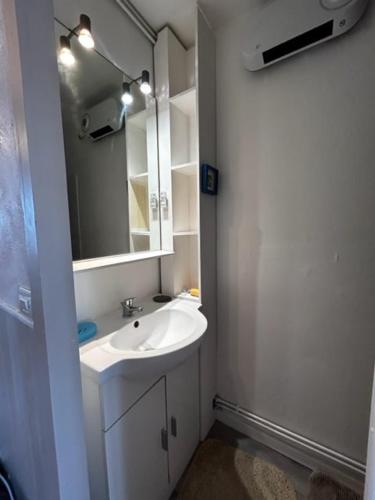 a white bathroom with a sink and a mirror at Tamaris 42 in Quend-Plage