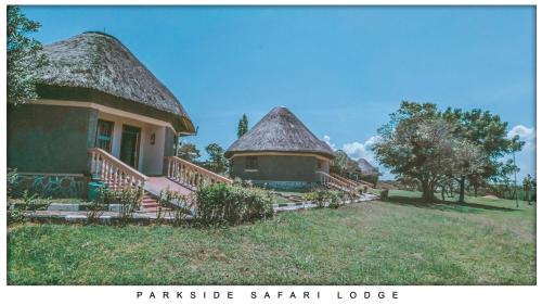 a house with a thatched roof and stairs to a building at Parkside Safari Lodge in Pakwach East