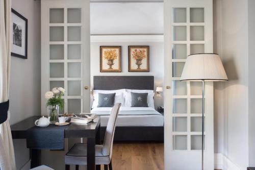 a bedroom with a bed and a desk and a table with a chair at Tornabuoni Suites Collection Residenza D'Epoca in Florence