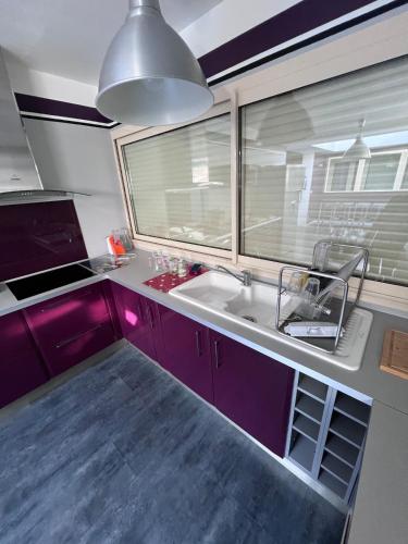 d'une cuisine avec des placards violets, un évier et une fenêtre. dans l'établissement La maison fitness, à Castang