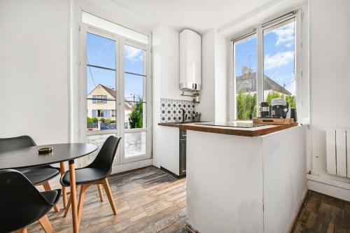 une cuisine avec une table, des chaises et des fenêtres dans l'établissement Le Cocon - Studio Proche Disney & Paris - Wifi, à Lagny-sur-Marne