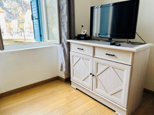 a tv on top of a white dresser in a room at Le Domaine d'Arignac in Arignac