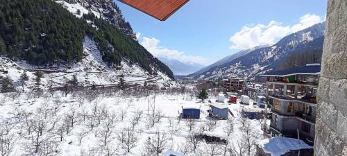 a view of a town in the snow with mountains at Treebo Premium Silverstone Resort With Mountain Valley View in Manāli