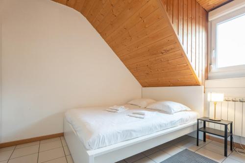- une chambre avec un lit blanc et un plafond en bois dans l'établissement Bel appartement 3Pers Stationnement Gratuit Centre, à Mulhouse