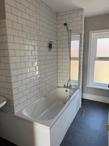 a white bath tub in a bathroom with a window at Stylish One Bedroom Apartment in Norwich