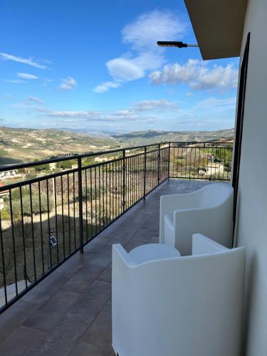 a balcony with white chairs and a view at Villa Baglio della Fico a 15 minuti dalla valle dei templi e dal mare in Racalmuto