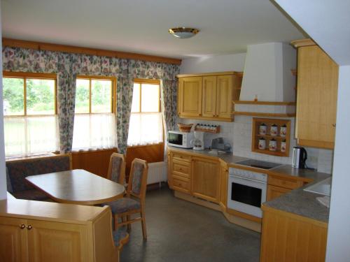 eine Küche mit Holzschränken, einem Tisch und einem Esszimmer in der Unterkunft Holiday-Appartements in Flachau