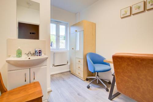 a bathroom with a sink and a desk with a blue chair at Hot Tub Stay Near Windsor & Legoland Sleeps 14 in Windsor