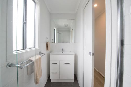 a white bathroom with a sink and a mirror at BIG4 Mannum Holiday Park in Mannum