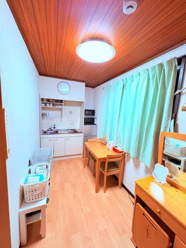 a room with a desk and a table and a kitchen at hostel sunflower201 in Osaka