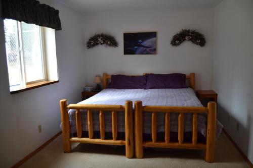 a bedroom with a wooden bed and two windows at All Seasons B&B in Kenai