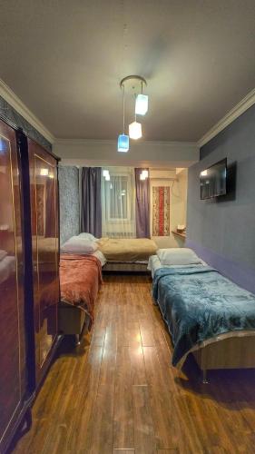 a room with two beds in a room with wooden floors at Apple Hotel in Yerevan