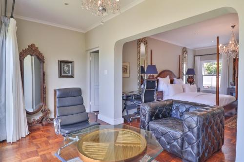 a bedroom with a bed and a couch and a table at The Gregoire Boutique Villa in Hermanus