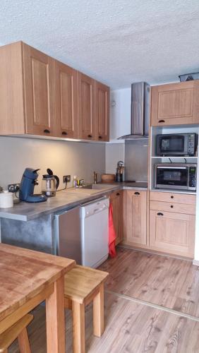 une cuisine avec des armoires en bois et des appareils en acier inoxydable dans l'établissement Renovated Duplex Apartment - 8 guests, aux Orres