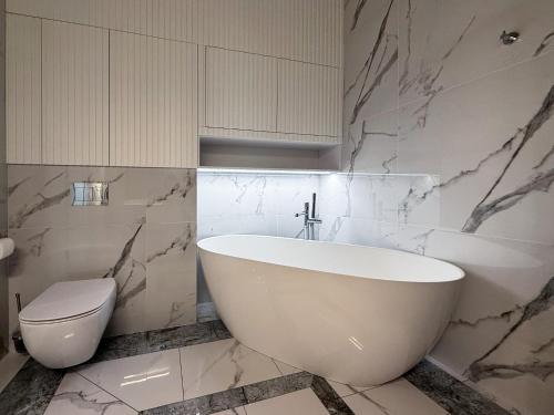 a white bathroom with a tub and a toilet at Bursztynowe Resort&SPA Stegna in Stegna