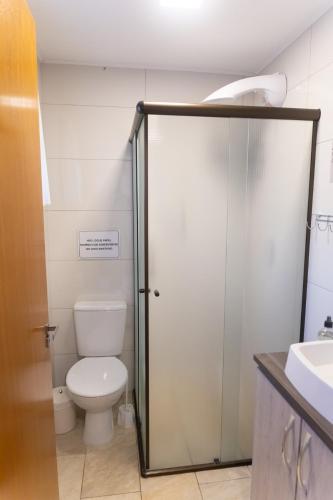 a bathroom with a toilet and a glass shower door at Pousada Chalés do Vale - Vale dos Vinhedos in Bento Gonçalves