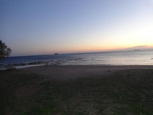 a beach at sunset with boats in the water at Nicholas Waves Beach Studios in Lardos