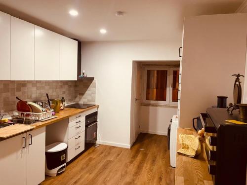 a kitchen with white cabinets and a wooden floor at Lisbon Soul Surf Camp in Cascais
