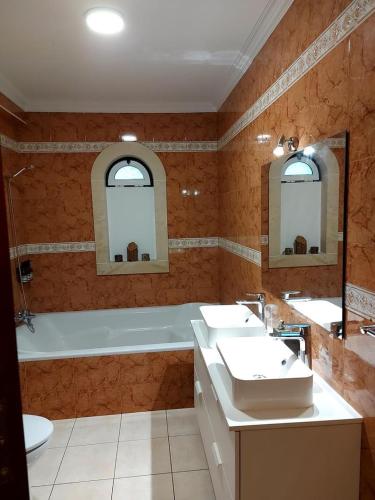 a bathroom with two sinks and a tub with two mirrors at Casa Botanica in Vestiaria