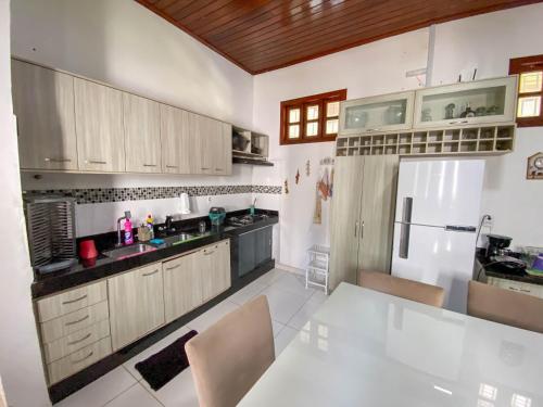 a kitchen with a table and a white refrigerator at CASA NA PRAIA - 5 QUARTOS - PISCINA - CHURASQUEIRA e VISTA EXTRAORDINARIA - 20 PESSOAS in Santarém
