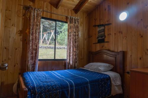 a bedroom with a bed and a window in a cabin at Cabañas Altos de carewe 2, Lican Ray Chile in Licán Ray