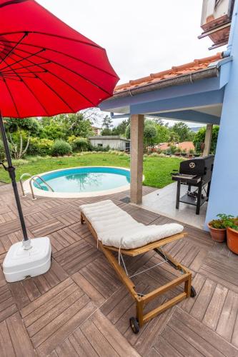 a chair and an umbrella on a deck with a pool at Casa Azul Belgica, Fiscal in Fiscal