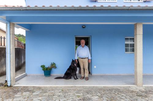 a man and a black dog sitting in a blue building at Casa Azul Belgica, Fiscal in Fiscal