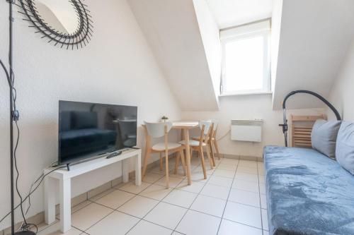 Il comprend un salon doté d'une télévision et d'une table avec des chaises. dans l'établissement Bel appartement 4Pers Stationnement Gratuit Centre, à Mulhouse