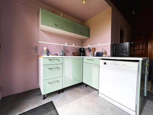 a kitchen with green cabinets and a white dishwasher at chalet in a quiet area, total disconnection in Ploubazlanec