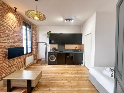 Il dispose d'une cuisine et d'un salon avec un mur en briques. dans l'établissement L'Argentier - Centre - Luxe - Gare, à Toulouse