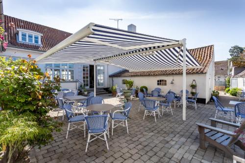 a patio with tables and chairs under a white canopy at Rødvig Kro og Badehotel in Rødvig