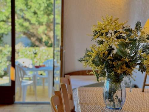 un vase rempli de fleurs jaunes sur une table dans l'établissement Colibri - Studio à 500m des plages, à Mimizan-Plage