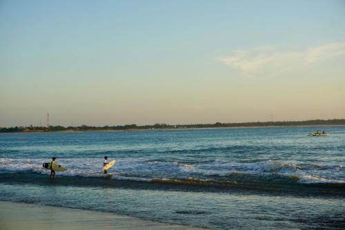 two people walking on the beach with their surfboards at Kudah Bay Surf Camp in Arugam Bay
