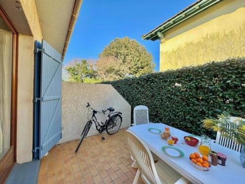 - un vélo garé sur une terrasse avec une table et des fruits dans l'établissement Mésange - Studio à 500m des plages, à Mimizan-Plage
