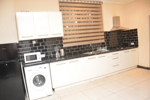 a kitchen with a washing machine and a microwave at Amareen Apartments in Accra