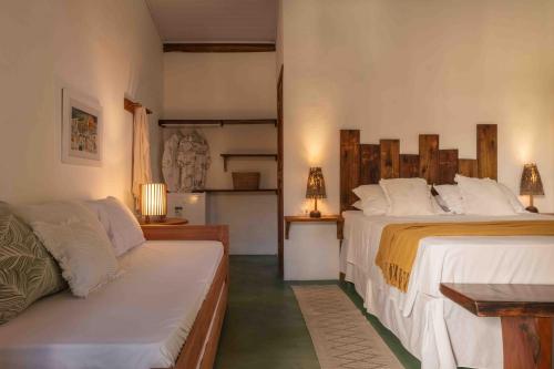 a bedroom with two beds and a couch at Suítes Aracuã in Caraíva