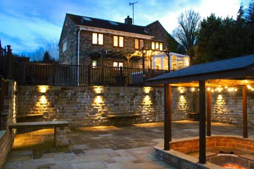 a building with a stone wall with a bench and lights at Rural Retreat with Hot Tub, Fire Pit & Games Room in Sheffield