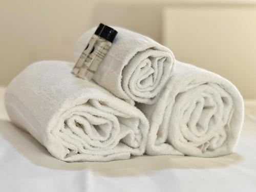 - une pile de serviettes assises sur un lit dans l'établissement Le Boutonnier - Centre - Luxe - Terrasse - Clim, à Toulouse