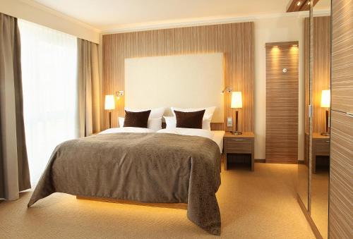 a bedroom with a large bed and a large window at Strandhotel Duhnen in Cuxhaven