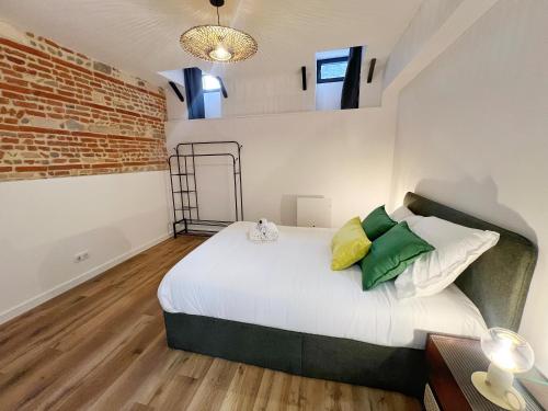 une chambre avec un lit et un mur de briques dans l'établissement Le Boutonnier - Centre - Luxe - Terrasse - Clim, à Toulouse