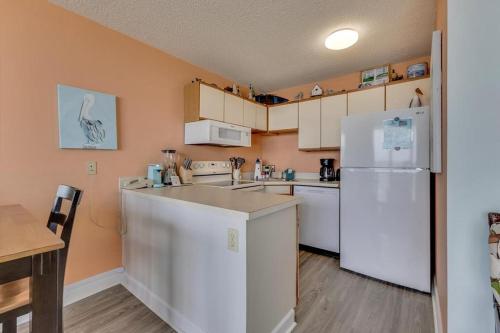 Una cocina con electrodomésticos blancos y un refrigerador blanco. en 0411 Seaside Sunrise by Atlantic Towers, en Carolina Beach