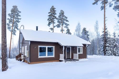 a cabin in the woods with snow on the roof at Holiday Cabin Villa Kalle in Himos