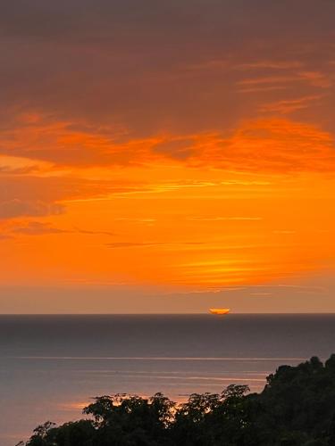 an orange sunset over the ocean with the sun in the sky at A & L Resort - Sea & Mountain View in Looc