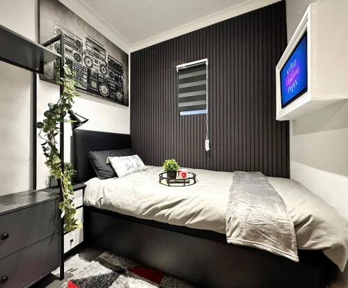 a bedroom with a bed with a tv on the wall at Boutique Backyard Bungalow - Brimsdown in Enfield Lock
