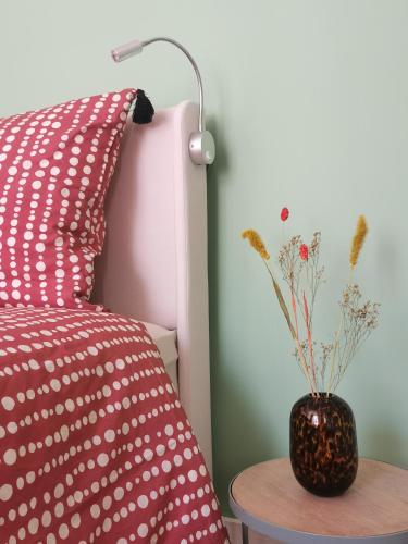 un vase assis sur une table à côté d'un lit dans l'établissement Lovely and bright studio in Montmartre, à Paris